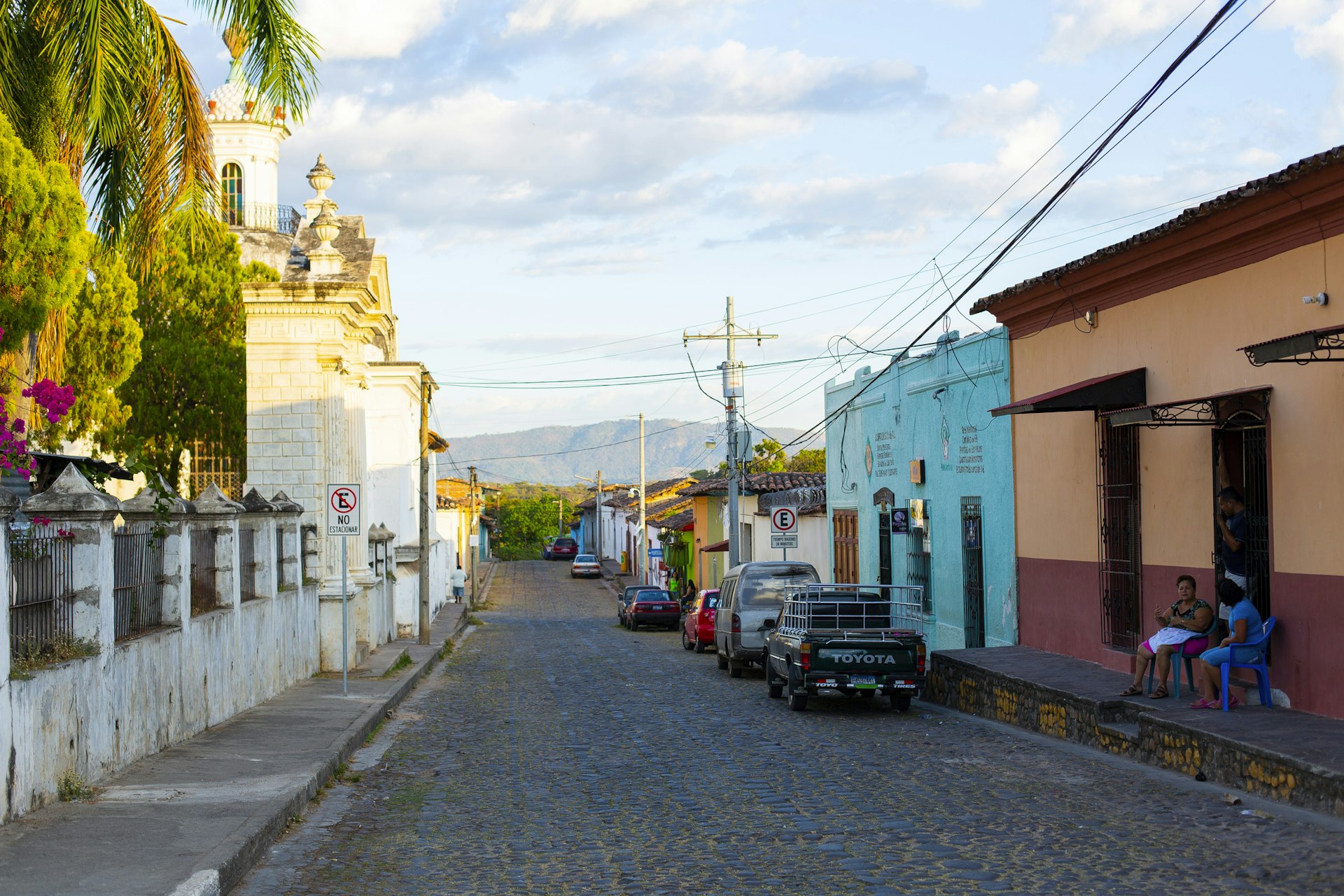 Street scene, two persons sitting in front of a house, beautiful sunlight and sky